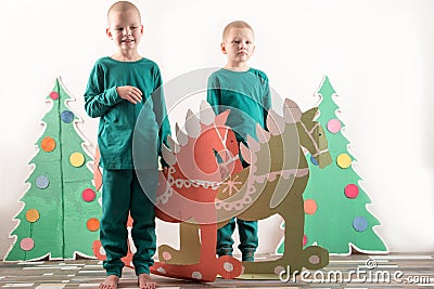 Two funny boys in a Santa Claus hat are playing with horses drawn on cardboard. The guys have fun at home. Christmas holiday conce Stock Photo