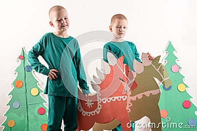 Two funny boys in a Santa Claus hat are playing with horses drawn on cardboard. The guys have fun at home. Christmas holiday conce Stock Photo