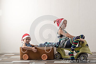 Two funny boys in a Santa Claus hat are playing with horses drawn on cardboard. The guys have fun at home. Christmas holiday conce Stock Photo