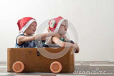 Two funny boys in a Santa Claus hat are playing with horses drawn on cardboard. The guys have fun at home. Christmas holiday conce Stock Photo