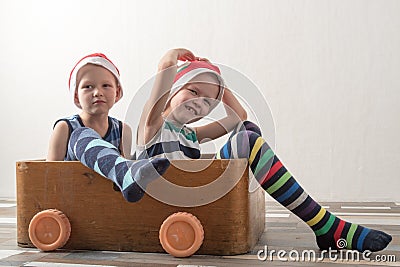 Two funny boys in a Santa Claus hat are playing with horses drawn on cardboard. The guys have fun at home. Christmas holiday conce Stock Photo