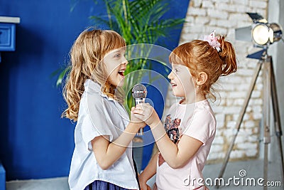 Two funny kids sing a song in karaoke. The concept is childhood, Stock Photo