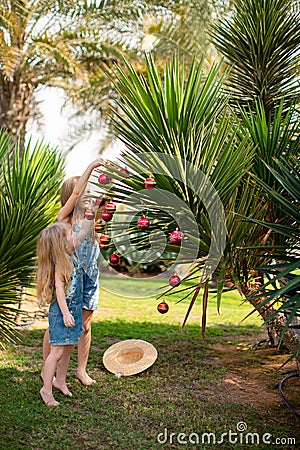 Kids girls dress up palm tree with Christmas toys Stock Photo