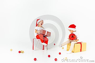 Two funny little kids in Santa hat sitting on gift boxes. Isolated on white background. Christmas and new year concept Stock Photo