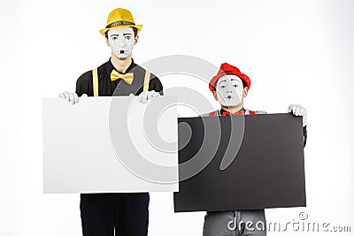 Two funny mimes holding a white blank on a white background. Stock Photo
