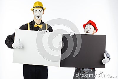 Two funny mimes holding a white blank on a white background. Stock Photo