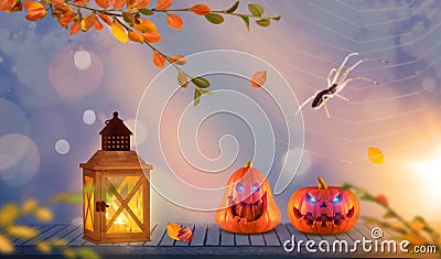 Two funny scary orange halloween pumpkins with glowing eyes onh wood with lantern with spider and a spider web in the background Stock Photo