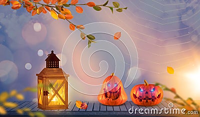 Two funny scary orange pumpkins with glowing eyes on wood and lantern at halloween evening Stock Photo