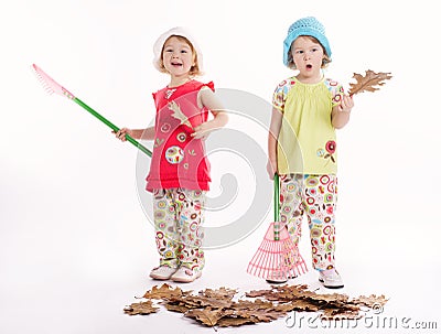 Two funny twins raking autumn leaves Stock Photo