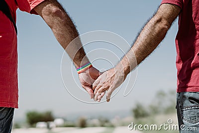 Two gay men shake hands with an LGBT bracelet.LGTB,LGBT Stock Photo