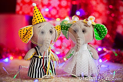 Two gift toy elephants stand on a background of Christmas lights and boxes Stock Photo