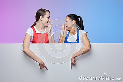 Two girls in aprons pose with a white Billboard. advertising concept Stock Photo
