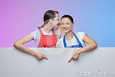 Two girls in aprons pose with a white Billboard. advertising concept Stock Photo