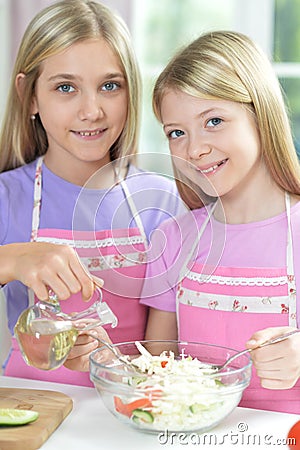 Two girls in aprons preparing fresh salad Stock Photo