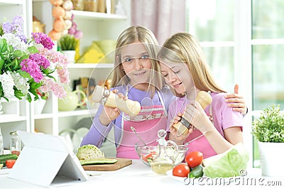 Two girls in aprons preparing fresh salad Stock Photo