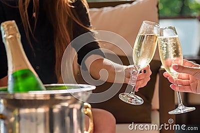 Two girls clink glasses of champagne on a beautiful summer terrace. sparkling champagne glasses Stock Photo