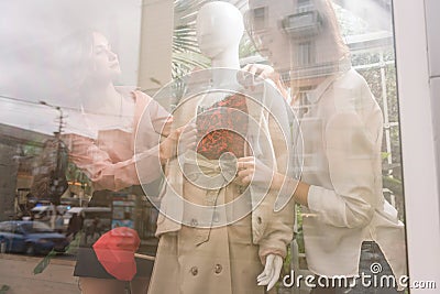 Two girls dress up mannequin at store front window Stock Photo