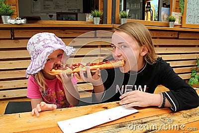 Two girls eat one big sandwich at at the same time. Childs divide one sandwich Stock Photo
