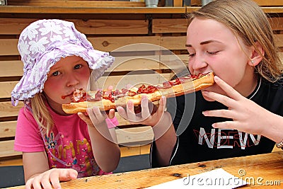 Two girls eat one big sandwich at at the same time Stock Photo