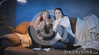 Two girls got scared while watching scary horror movie on TV at night Stock Photo