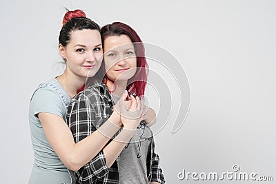 Two girls hug on a white background. Homosexual lesbian couple. Casual clothes. Stock Photo