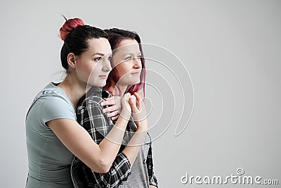 Two girls hug on a white background. Homosexual lesbian couple. Casual clothes. Stock Photo