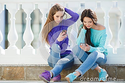 Two girls listening to music on their smartphones. Stock Photo