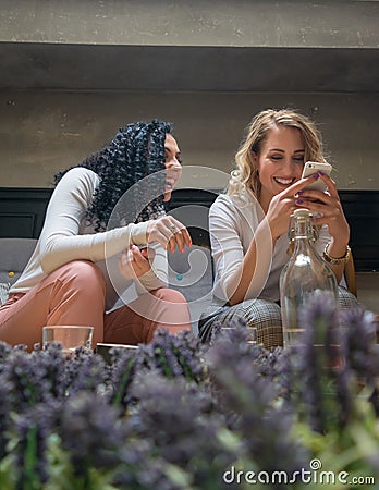 Two girls are looking at the phone and smiling in cafe Stock Photo