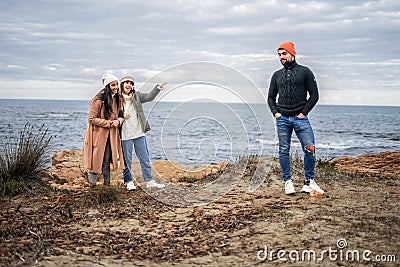 Two girls make fun of a guy outdoors by pointing that he has an amused expression. Three best multiracial friends having fun Stock Photo