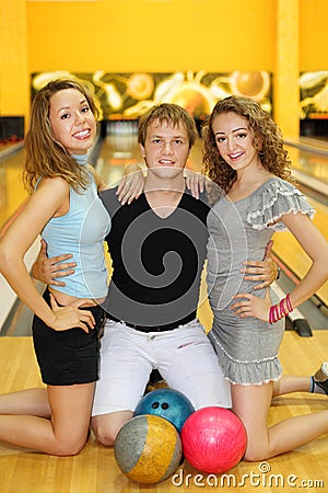 Two girls and man kneel on floor in bowling club Stock Photo