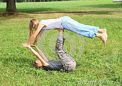 Two girls playing and exercising yoga on meadow Stock Photo