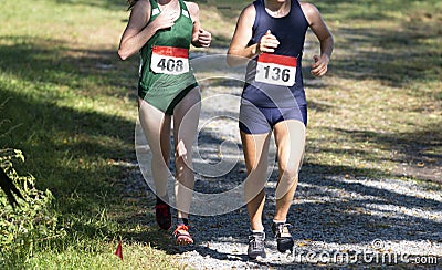 Two girls racing downhill during a chigh school ross country race Stock Photo