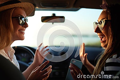 Happy excited young women driving in car and making high five gesture on summer vacation trip. Two girls rejoice they Stock Photo