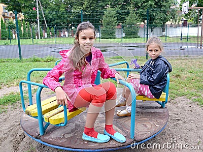 Two girls ride a carousel. Playground Stock Photo