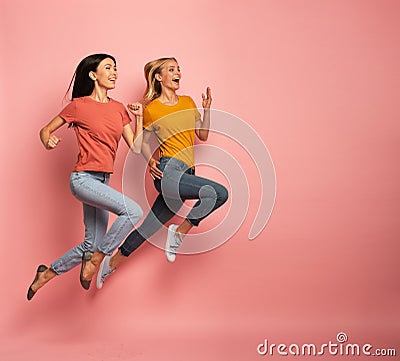 Two girls run fast. Concept of energy and vitality. Pink background Stock Photo