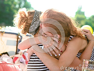 Two girls sea striped shirts hug outside Stock Photo