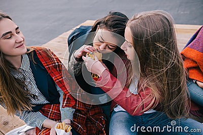 Two girls sharing one burger. Close friendship Stock Photo