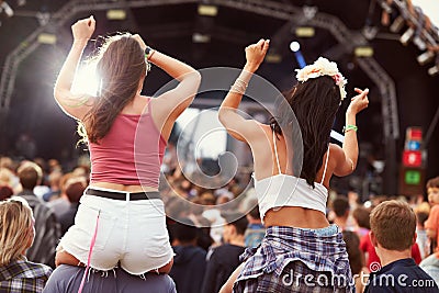 Two girls on shoulders in the crowd at a music festival Stock Photo