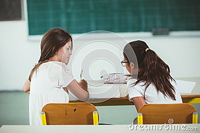 Two girls sit at school desks and look toward blackboard Stock Photo