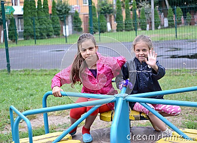 Two girls are sitting on a carousel. Playground Stock Photo