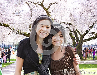 Two girls standing in front of large flowering cherry tree Stock Photo