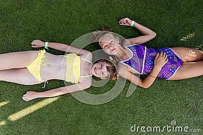 Two girls in swimsuit are having fun on the grass by the pool Stock Photo