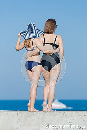 Two girls in swimsuits against the sky, rear view Stock Photo