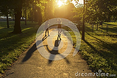 Two girls walking down the alley holding hands, during amazing sunset. Stock Photo