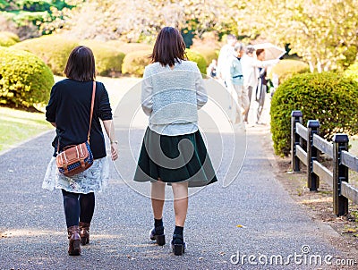 Two girls walking on a road in a city park, Tokyo, Japan. Copy s Editorial Stock Photo