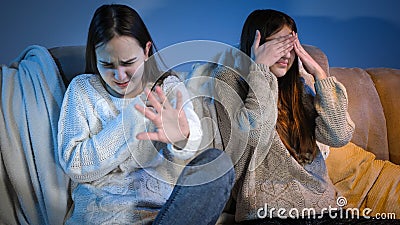 Two girls watching scary or bad TV show and feeling disgusting Stock Photo