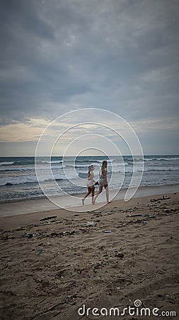 Two girls were walking along the kuta beach denpasar bali Editorial Stock Photo