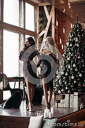 Two glamorous girls standing near christmas tree and posing Stock Photo