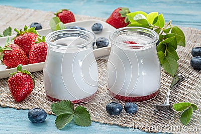 Two glass containers with plain yoghurt and berries on the table. Light summer mood Stock Photo