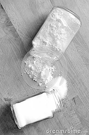 Two glass jars overflow sugar and flour on the wooden kitchen ta Stock Photo
